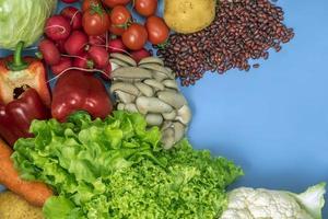 Products for a vegetarian detox diet of cauliflower, lettuce, radishes, tomatoes, mushrooms, beans, and red bell pepper on a blue background photo