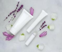 Cosmetic skincare background of Petri dishes and cosmetic tubes of herbal medicine with green leaves and petals