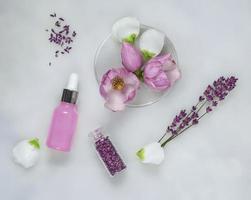 Cosmetic skincare background of Petri dishes and cosmetic tubes of herbal medicine with green leaves and petals photo