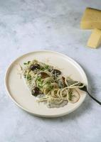 Un plato de pasta con queso y salsa de champiñones sobre un fondo de mármol gris foto