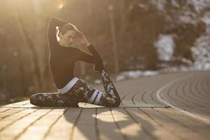 A young athletic woman performs yoga and meditation exercises outdoors photo