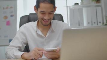 El empresario asiático utiliza el teléfono y la pantalla táctil en la oficina video