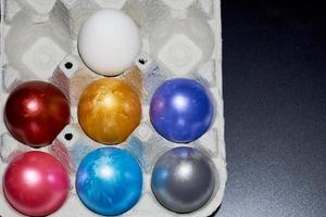 huevos de pascua de color nacarado en un cartón de huevos foto