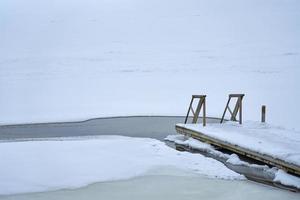 A wooden staircase leading into an ice hole photo