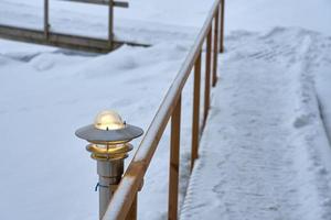 Lantern on a snow-covered path with wooden railings in winter photo