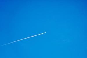 A trail from a plane in the clear blue sky photo