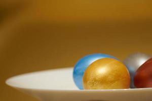 Huevos de pascua de color nacarado en un cartón de huevos sobre un fondo dorado foto