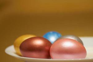 Huevos de pascua de color nacarado en un cartón de huevos sobre un fondo dorado foto