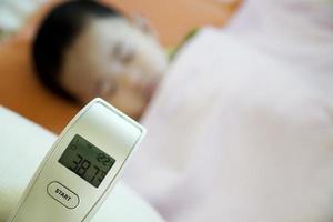 Sick child with thermometer showing fever photo