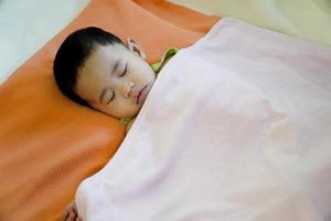 Close-up of a baby sleeping in bed photo