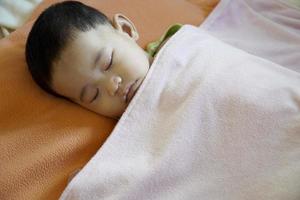 Close-up of a baby sleeping in bed photo