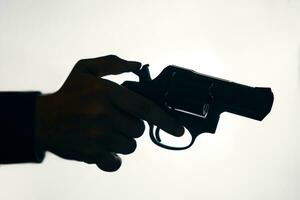 Silhouette of man's hand with revolver on white background photo