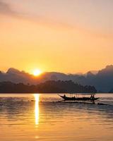 silhouette image of a  boat sailing in a dam in southern of Thailand in the morning.