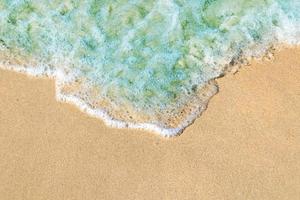 Soft waves with foam of blue ocean on the sandy beach photo