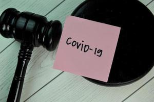 Covid-19 written on a notepad with gavel isolated on wooden table photo