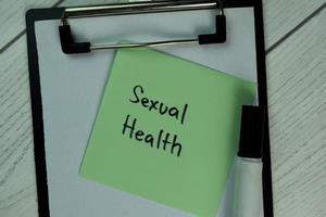 Sexual health written on notepad isolated on wooden table photo