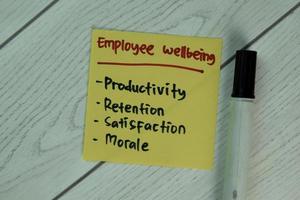 Employee wellbeing written on notepad isolated on wooden table photo