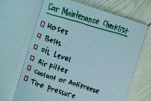 Car maintenance checklist written on a book with additional services isolated on wooden table photo