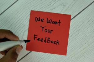 We want your feedback written on notepad isolated on wooden table photo