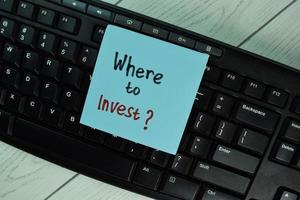 Where to invest written on notepad isolated on wooden table photo