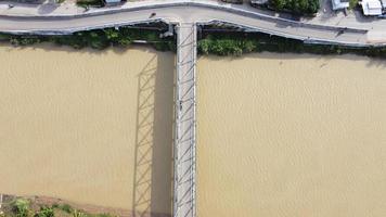 Bekasi, Indonesia 2021- Aerial drone view of a long bridge at the end of the river connecting two villages photo