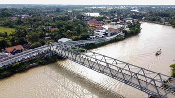 Bekasi, Indonesia 2021- Aerial drone view of a long bridge to the end of the river connecting  two villages