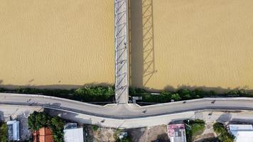 Bekasi, Indonesia 2021- Aerial drone view of a long bridge to the end of the river connecting  two villages photo