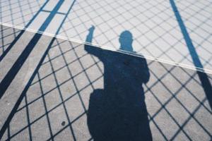 Man's shadow with a rope net on the ground photo