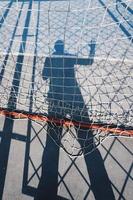 Man's shadow with a rope net on the ground photo