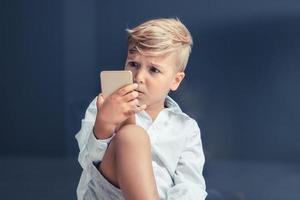 niño pequeño con teléfono móvil con incredulidad foto