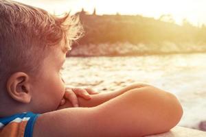 Close up of boy traveling by boat at sunset photo