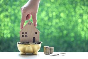 Stack of coins in piggy bank wood and model house on natural green background photo