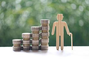 Senior man and stack of coins on natural green background photo