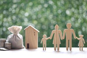 familia modelo y casa modelo con bolsa de dinero y pila de monedas foto