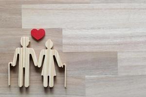 Wooden cutout of a couple and heart shape on wooden background photo