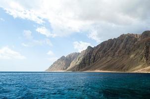 Blue sea and high rocky mountains photo