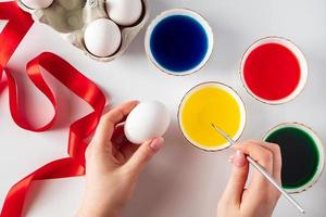 Young woman painting white eggs for easter photo