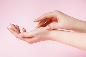 hermosas manos femeninas sobre fondo rosa