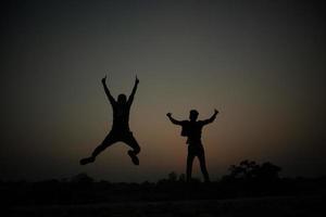 Silhouette of two happy guys photo