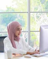 Hermosa empresaria musulmana trabajando felizmente en la oficina foto