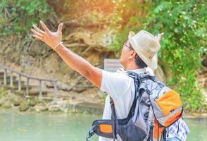 Asian traveler raises hands with pleasure to breathe fresh air while studying nature photo