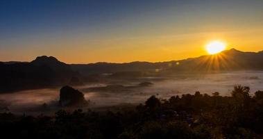 Sun rises over the mountains and the fog photo