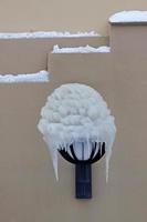 A wall lamp outdoors with heavy snow