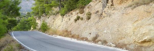 Asphalt road in the Mediterranean mountains covered with pine trees photo