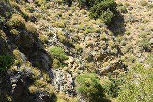 Old homemade wooden staircase that runs over rocks in a mountain gorge photo