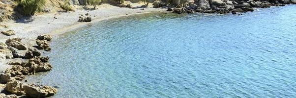 Beautiful blue lagoon with clear sea water and a pebble beach and rocks photo