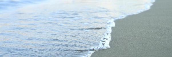 Blurred wave of the sea on the evening sand beach photo