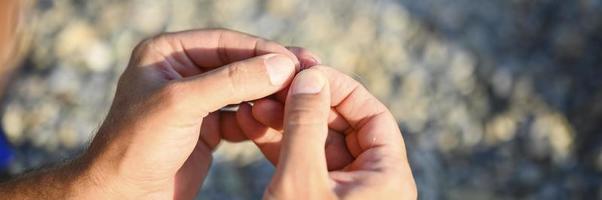 Man's hands tying a fishing line on a fishing hook photo