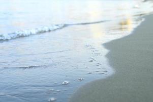 Blurred wave of the sea on the evening sand beach photo