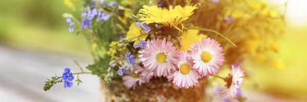 A bouquet of wildflowers of forget-me-nots, daisies and yellow dandelions in full bloom in a rustic jar photo